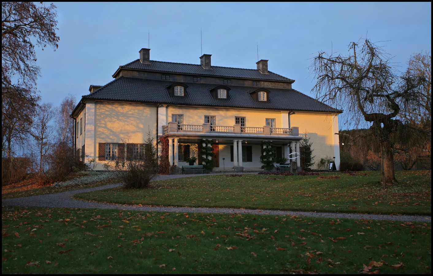 M�rbacka herrg�rd i V�rmland, Selma Lagerl�fs historiska hem. Bilden visar den ljusa byggnaden med m�rkt tak, omgiven av h�stf�rgad tr�dg�rd och gr�smatta.